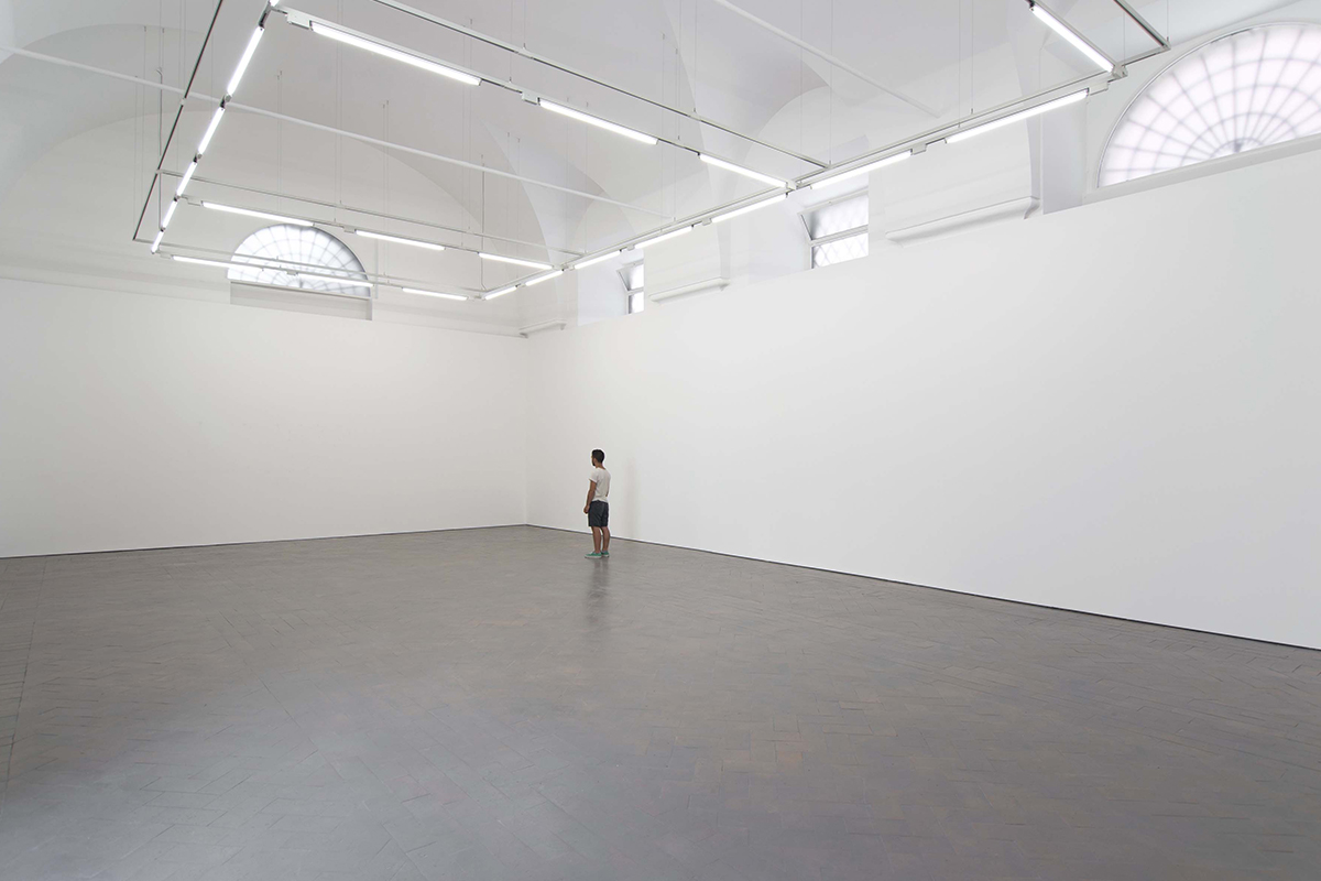man standing in a wide white art gallery