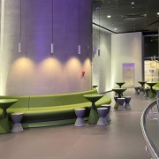 curving green bench, grey wall, tables